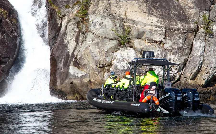 A RIB boat beneath a waterfall on the Hardangerfjord at Eidfjord
