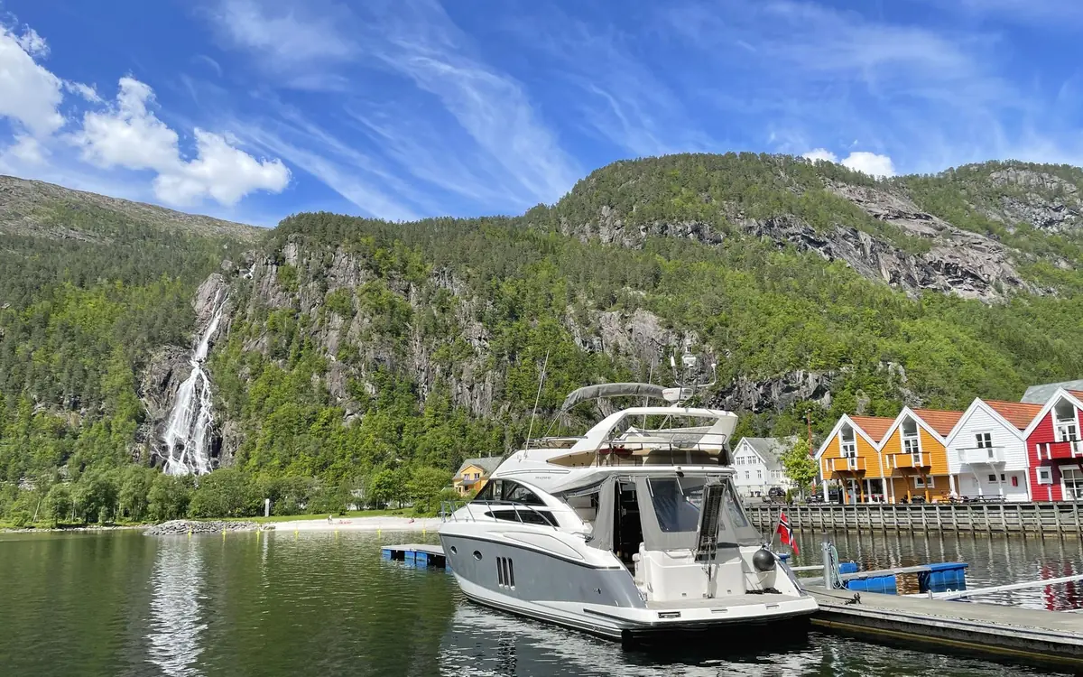Red wooden houses and a boat on the Hardangerfjord